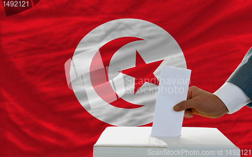 Image of man voting on elections in tunisia in front of flag