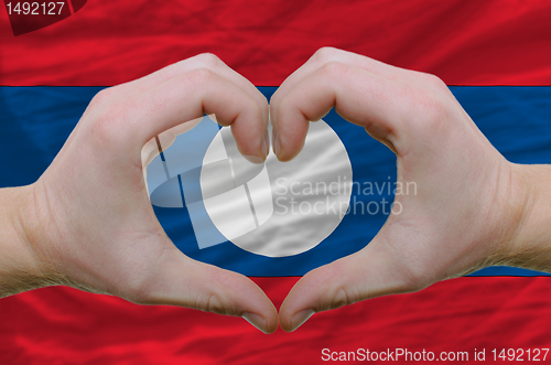 Image of Heart and love gesture showed by hands over flag of laos backgro