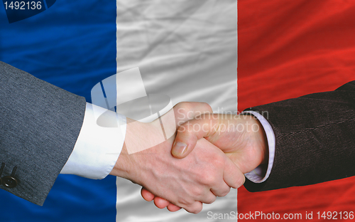 Image of businessmen handshake after good deal in front of france flag