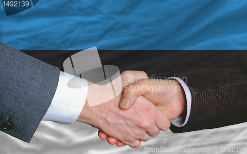 Image of businessmen handshake after good deal in front of estonia flag