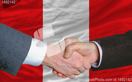 Image of businessmen handshake after good deal in front of peru flag