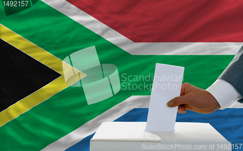 Image of man voting on elections in south africa in front of flag