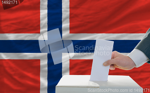 Image of man voting on elections in norway in front of flag