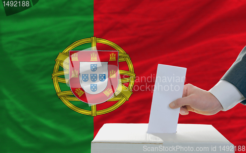 Image of man voting on elections in portugal in front of flag