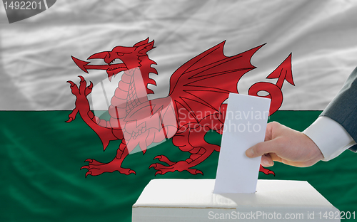 Image of man voting on elections in wales in front of flag