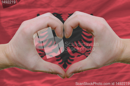 Image of Heart and love gesture showed by hands over flag of Albania back