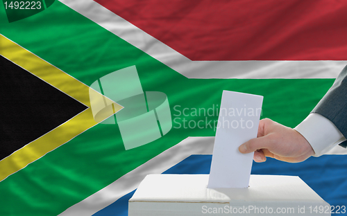 Image of man voting on elections in south africa in front of flag