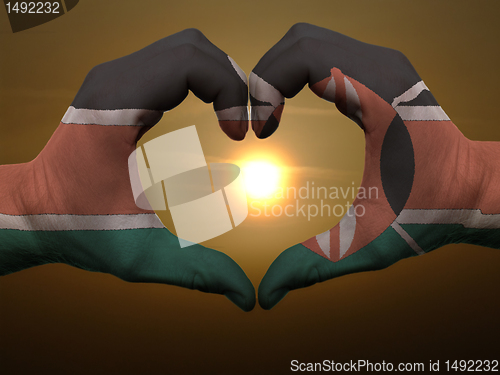 Image of Heart and love gesture by hands colored in kenya flag during bea