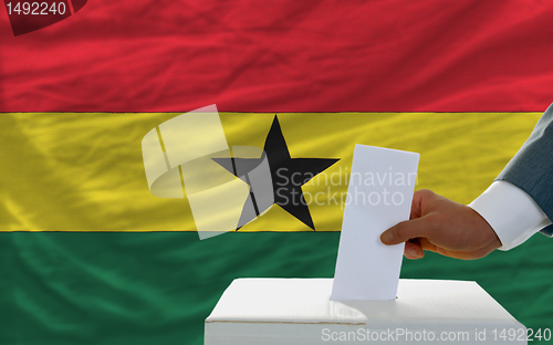 Image of man voting on elections in ghana in front of flag