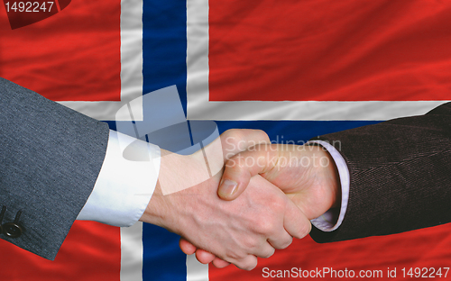 Image of businessmen handshake after good deal in front of norway flag