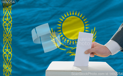 Image of man voting on elections in kazakhstan in front of flag