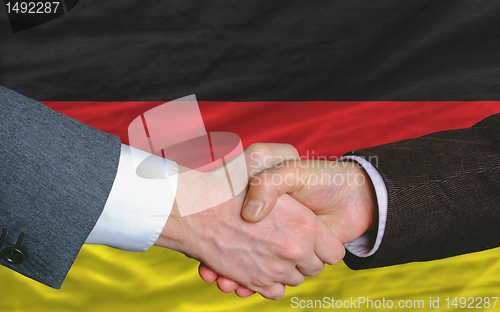 Image of businessmen handshake after good deal in front of germany flag