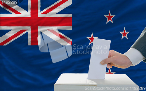 Image of man voting on elections in new zealand in front of flag