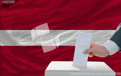 Image of man voting on elections in latvia in front of flag