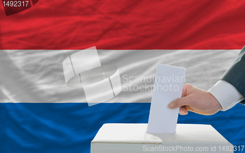 Image of man voting on elections in netherlands in front of flag