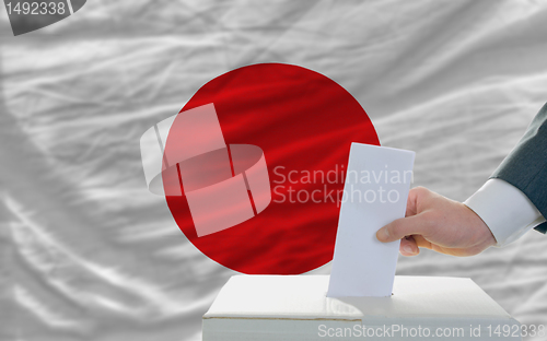 Image of man voting on elections in japan in front of flag