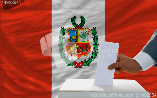 Image of man voting on elections in peru in front of flag