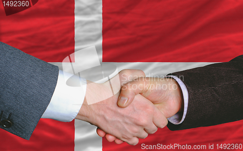 Image of businessmen handshake after good deal in front of denmark flag