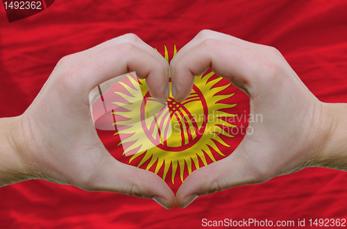 Image of Heart and love gesture showed by hands over flag of kyrghyzstan 