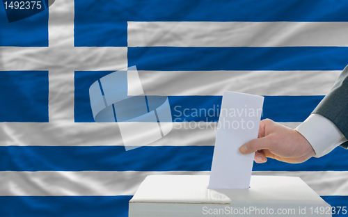 Image of man voting on elections in greece in front of flag