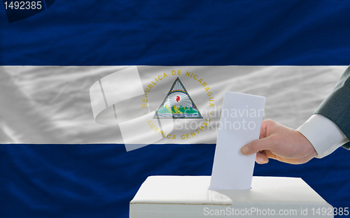 Image of man voting on elections in nicaragua in front of flag