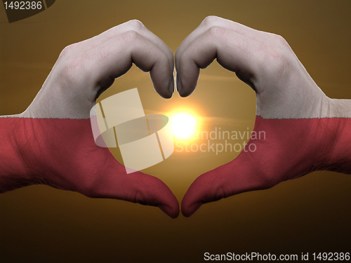 Image of Heart and love gesture by hands colored in poland flag during be