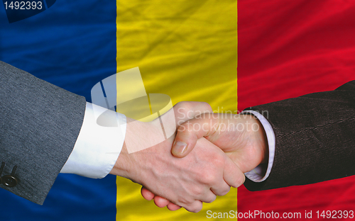 Image of businessmen handshake after good deal in front of romania flag