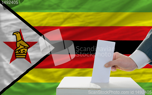 Image of man voting on elections in zimbabwe in front of flag