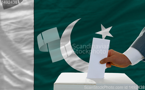Image of man voting on elections in pakistan in front of flag