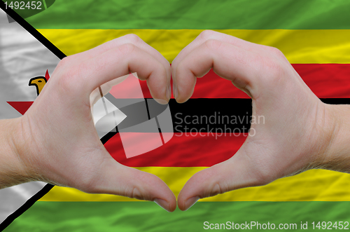 Image of Heart and love gesture showed by hands over flag of zimbabwe bac