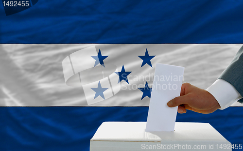 Image of man voting on elections in honduras in front of flag