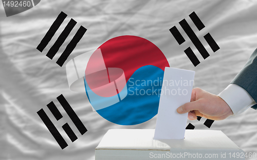 Image of man voting on elections in south korea in front of flag