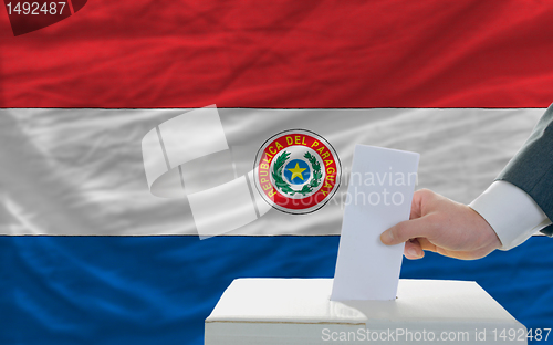 Image of man voting on elections in paraguay in front of flag