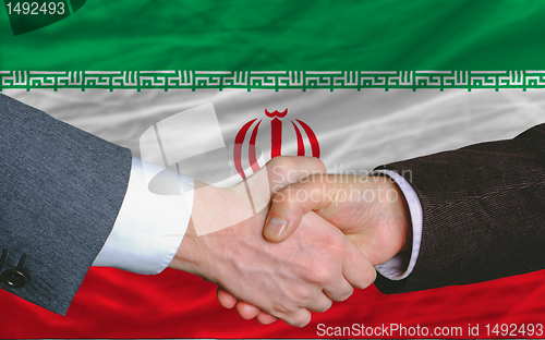 Image of businessmen handshake after good deal in front of iran flag