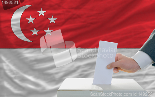 Image of man voting on elections in singaporel in front of flag