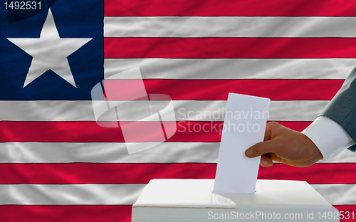 Image of man voting on elections in liberia in front of flag