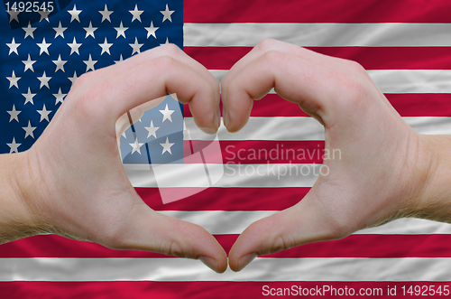 Image of Heart and love gesture showed by hands over flag of usa backgrou