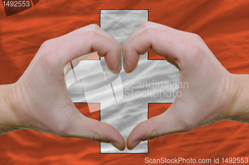 Image of Heart and love gesture showed by hands over flag of schwitzerlan