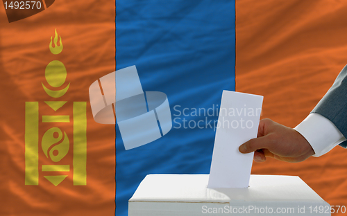 Image of man voting on elections in mongolia in front of flag