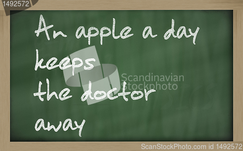 Image of " An apple a day keeps the doctor away " written on a blackboard