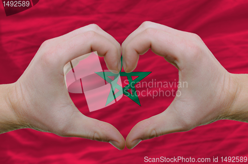Image of Heart and love gesture showed by hands over flag of morocco back