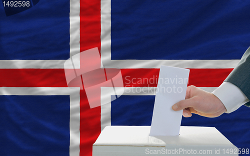 Image of man voting on elections in iceland in front of flag