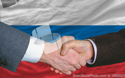 Image of businessmen handshake after good deal in front of russia flag