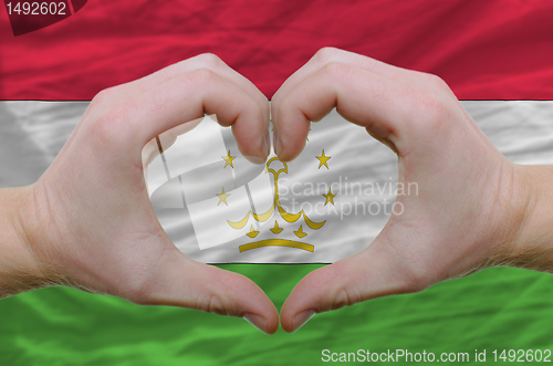 Image of Heart and love gesture showed by hands over flag of tajikistan b