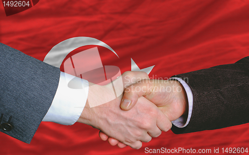Image of businessmen handshake after good deal in front of turkey flag