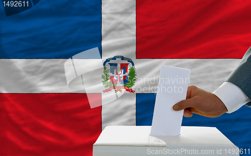 Image of man voting on elections in dominican republic in front of flag