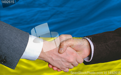 Image of businessmen handshake after good deal in front of ukraine flag