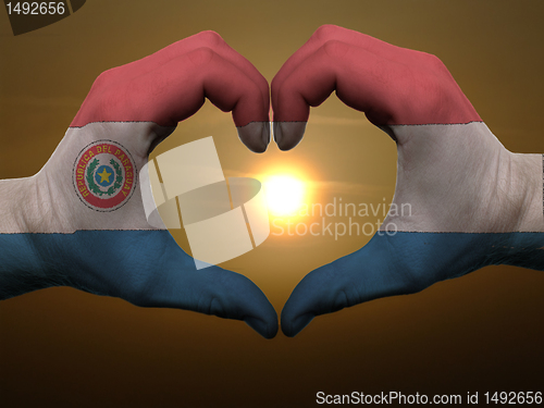 Image of Heart and love gesture by hands colored in paraguay flag during 