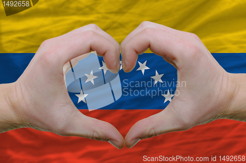 Image of Heart and love gesture showed by hands over flag of venezuela ba