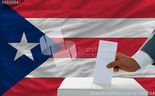 Image of man voting on elections in puertorico in front of flag